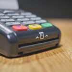 Commerciante che utilizza un POS per elaborare un pagamento, evidenziando le nuove regole.